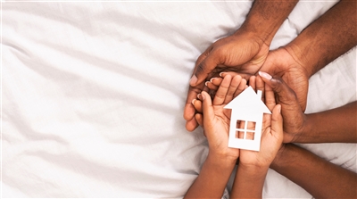 family of three holding paper house figure in hands